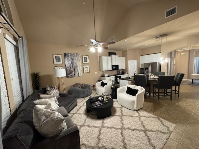 living room with light tile patterned floors, visible vents, arched walkways, ceiling fan, and high vaulted ceiling