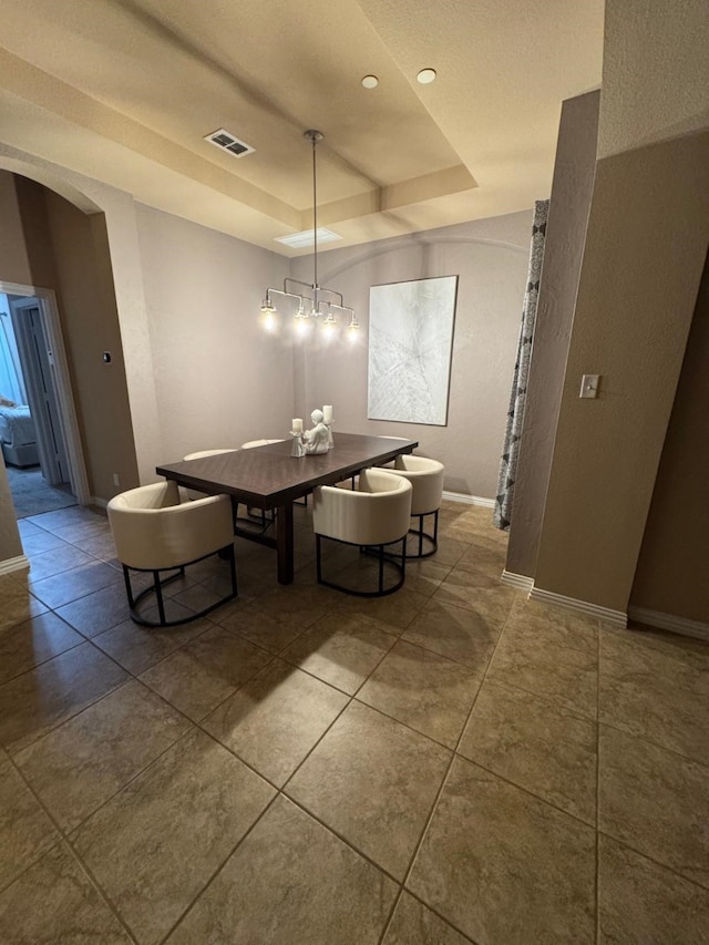 tiled dining room with arched walkways, recessed lighting, visible vents, baseboards, and a tray ceiling