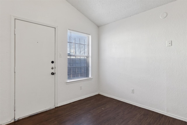 foyer entrance featuring dark wood-style flooring, vaulted ceiling, a textured ceiling, and baseboards