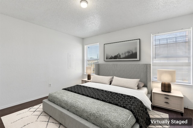 bedroom featuring a textured ceiling, baseboards, and wood finished floors