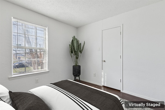 bedroom featuring a textured ceiling, dark wood-style flooring, and baseboards