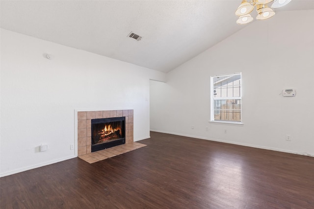 unfurnished living room featuring a chandelier, a tile fireplace, wood finished floors, visible vents, and baseboards