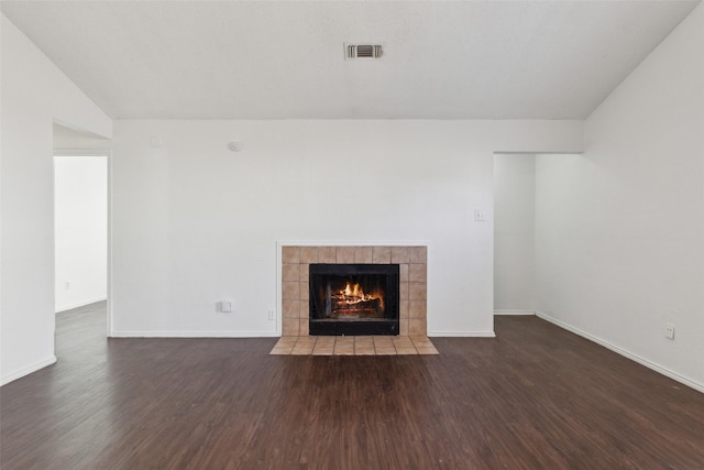 unfurnished living room with visible vents, vaulted ceiling, wood finished floors, a tile fireplace, and baseboards