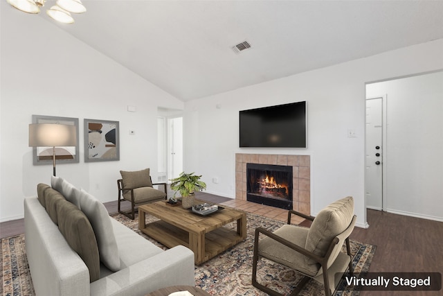 living area with a fireplace, lofted ceiling, visible vents, wood finished floors, and baseboards