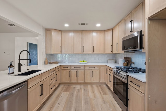 kitchen with visible vents, light countertops, stainless steel appliances, light brown cabinetry, and a sink