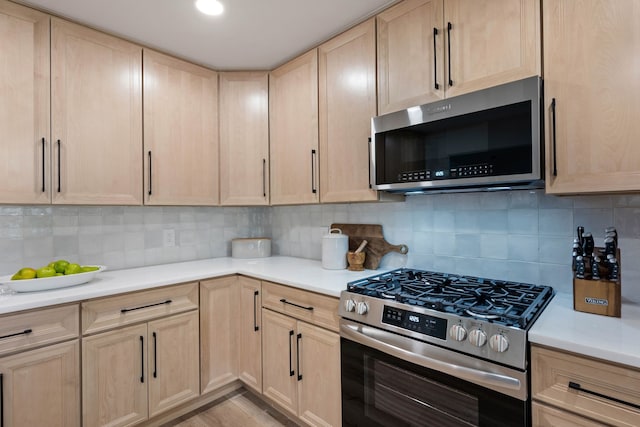 kitchen with tasteful backsplash, light brown cabinets, stainless steel appliances, and light countertops