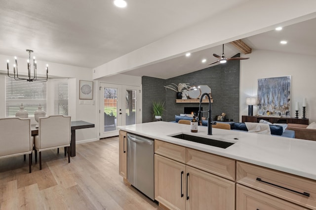 kitchen with lofted ceiling with beams, light brown cabinetry, open floor plan, a sink, and dishwasher