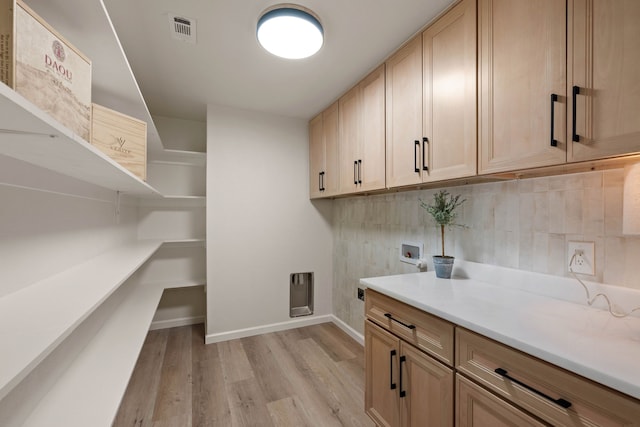 clothes washing area with washer hookup, visible vents, baseboards, light wood-style floors, and cabinet space