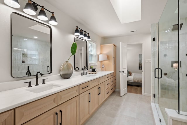 ensuite bathroom featuring a stall shower, a skylight, a sink, and double vanity