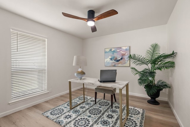 office featuring ceiling fan, baseboards, and light wood-style flooring