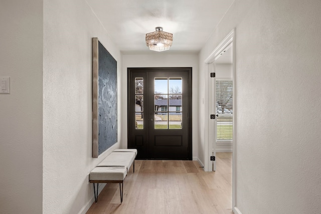 doorway to outside with baseboards, wood finished floors, and a textured wall