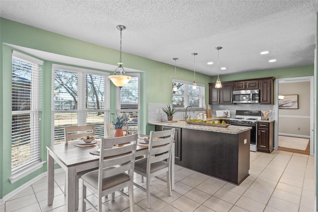 kitchen featuring range with gas stovetop, stainless steel microwave, dark brown cabinetry, and light tile patterned floors