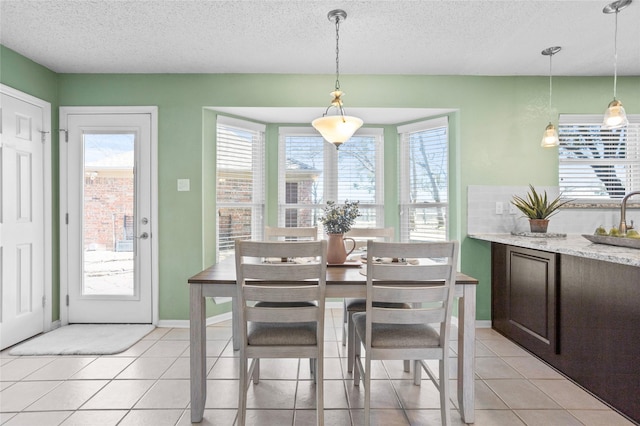 dining room with light tile patterned floors, a textured ceiling, and baseboards