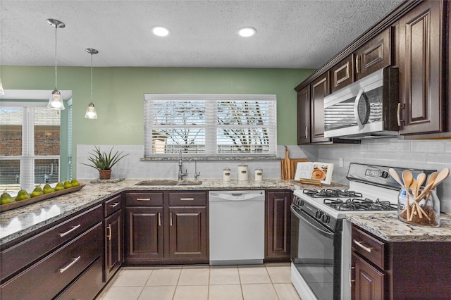 kitchen with stainless steel microwave, a sink, a wealth of natural light, dishwasher, and gas range oven