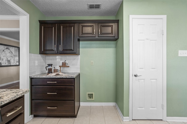 kitchen featuring visible vents, dark brown cabinetry, backsplash, and light tile patterned floors