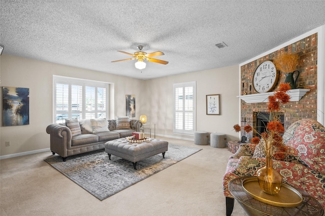 carpeted living room with ceiling fan, a fireplace, visible vents, and a textured ceiling