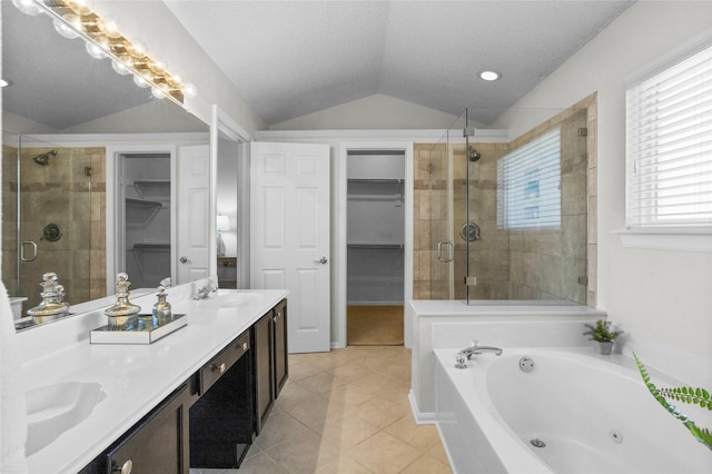 bathroom featuring a tub with jets, tile patterned floors, vaulted ceiling, a shower stall, and a sink