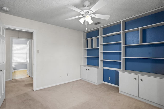 interior space featuring attic access, baseboards, visible vents, light colored carpet, and a textured ceiling