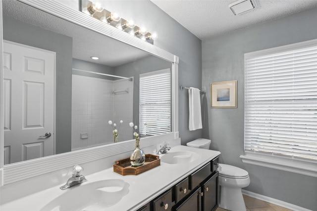 full bath featuring toilet, tile patterned floors, a sink, and tiled shower