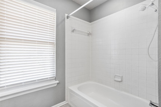 bathroom with washtub / shower combination, baseboards, and a textured ceiling