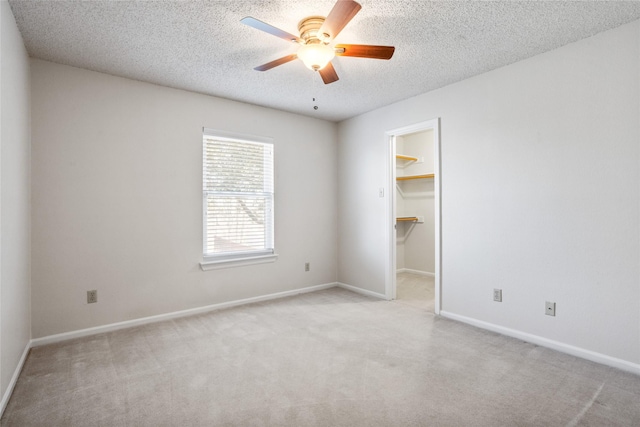 spare room featuring carpet floors, ceiling fan, baseboards, and a textured ceiling