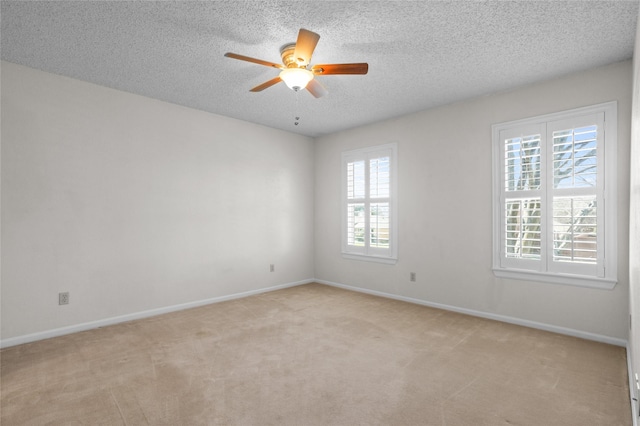 spare room featuring a textured ceiling, baseboards, a ceiling fan, and light colored carpet