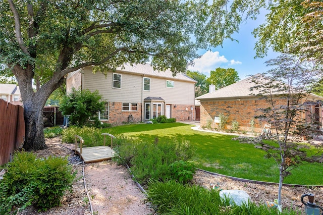 rear view of property with a fenced backyard, a lawn, and brick siding