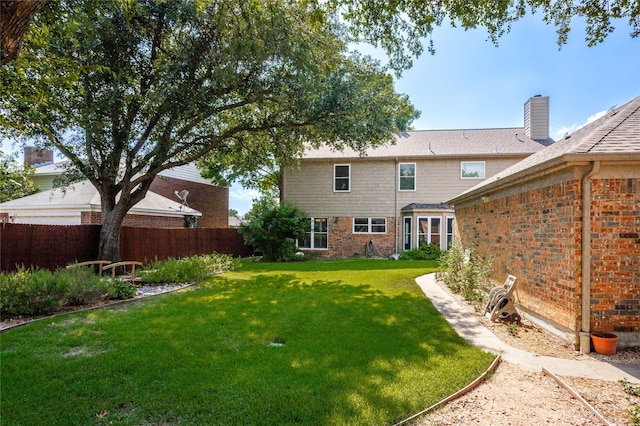 rear view of house featuring fence and a yard