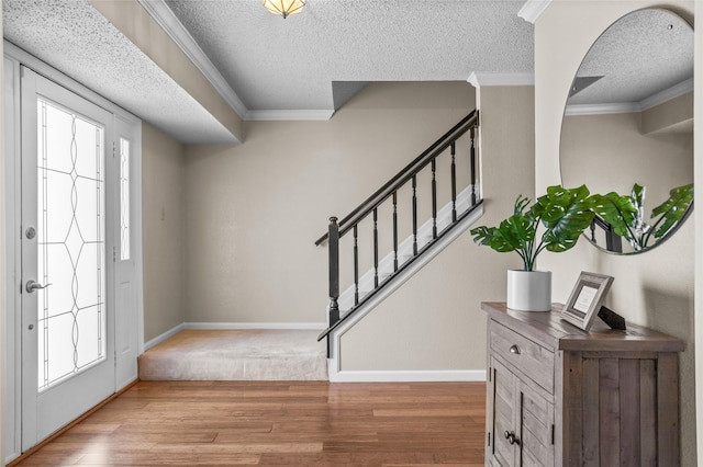 foyer entrance with baseboards, crown molding, stairway, and wood finished floors