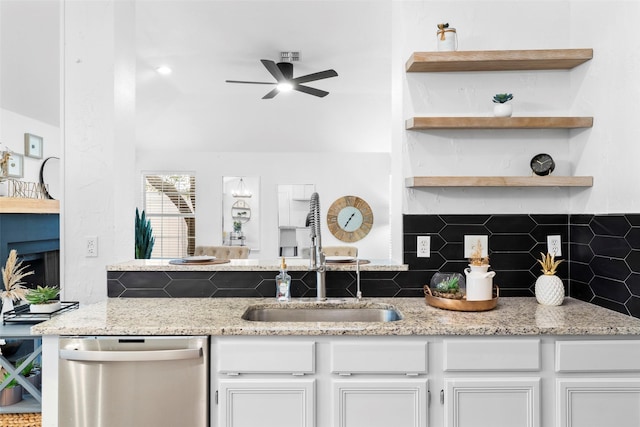 kitchen with tasteful backsplash, stainless steel dishwasher, white cabinetry, open shelves, and a sink