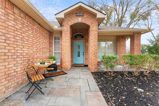 entrance to property with brick siding and roof with shingles