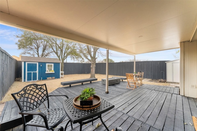 wooden deck with outdoor dining area, a fenced backyard, an outdoor structure, and a shed