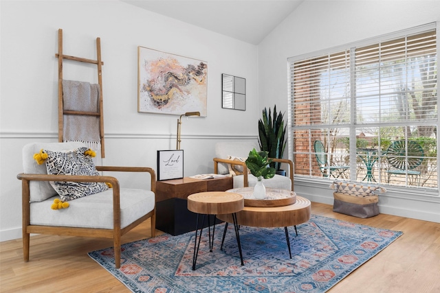 living area with baseboards, vaulted ceiling, and wood finished floors