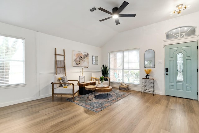 foyer entrance featuring a wealth of natural light, visible vents, lofted ceiling, and wood finished floors