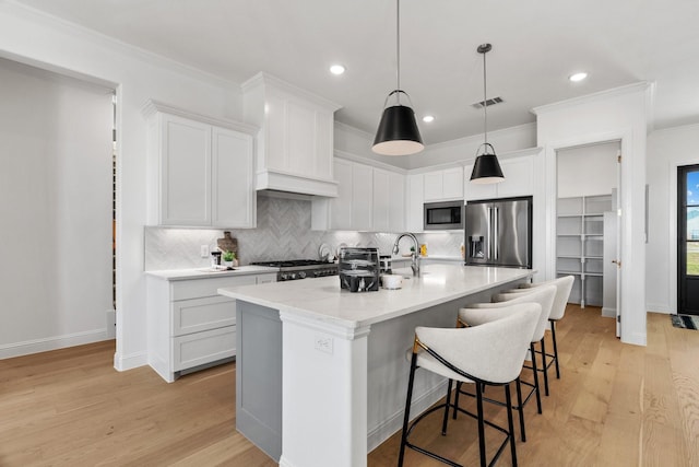 kitchen featuring appliances with stainless steel finishes, visible vents, a kitchen bar, and white cabinetry