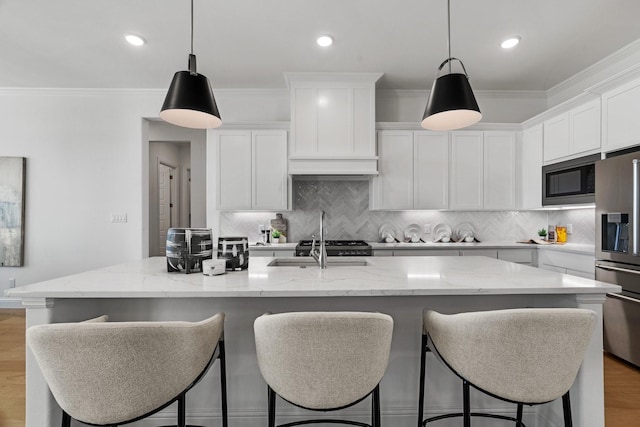 kitchen featuring decorative backsplash, light wood-style floors, a sink, black microwave, and stainless steel fridge