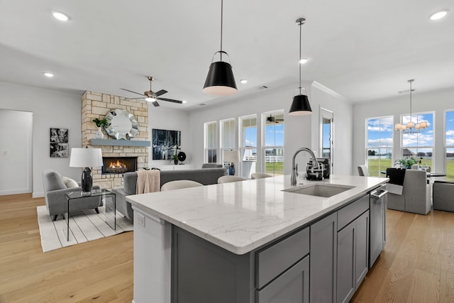 kitchen with open floor plan, a kitchen island with sink, a sink, and gray cabinetry