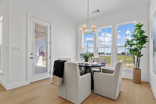 dining space with ornamental molding, light wood-type flooring, a chandelier, and visible vents