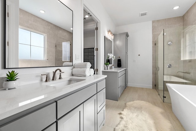 full bathroom featuring a freestanding tub, a stall shower, two vanities, and a sink