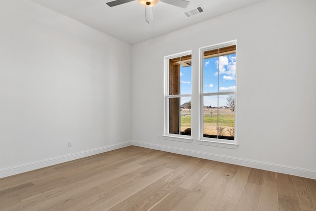 empty room with a ceiling fan, light wood-type flooring, visible vents, and baseboards