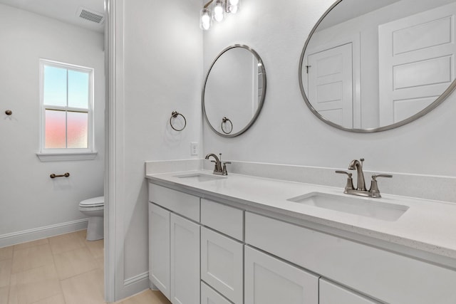 full bath featuring toilet, double vanity, visible vents, and a sink