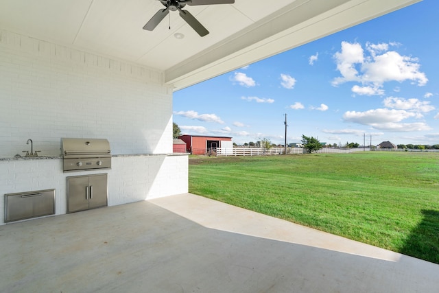 view of patio / terrace featuring grilling area, an outdoor kitchen, a sink, ceiling fan, and fence