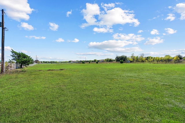 view of yard with fence and a rural view