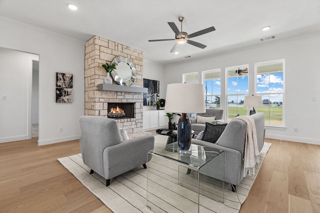 living room with ornamental molding, light wood-style flooring, a fireplace, and visible vents