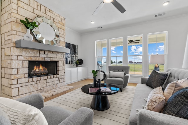 living room featuring ornamental molding, visible vents, ceiling fan, and wood finished floors