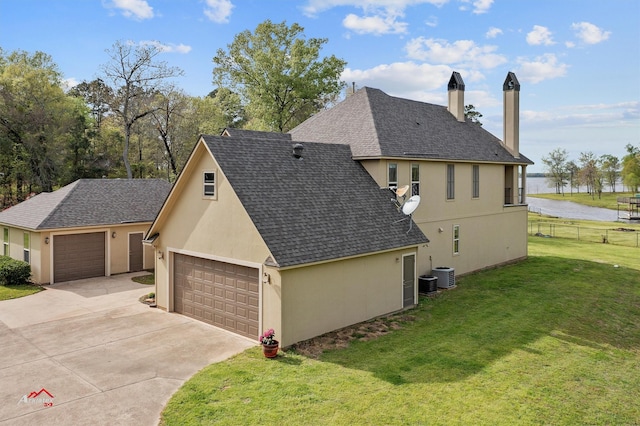 view of side of property with roof with shingles, stucco siding, central air condition unit, a lawn, and a garage