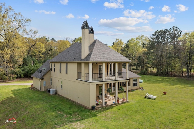 back of house featuring central AC, a shingled roof, a yard, a chimney, and a patio area