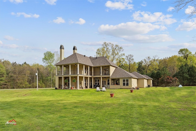 back of house featuring a balcony, a patio area, stucco siding, and a yard