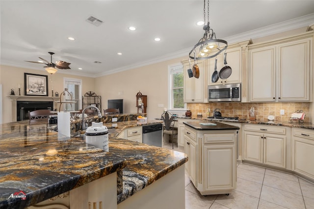 kitchen featuring cream cabinets, a fireplace, a kitchen island, visible vents, and appliances with stainless steel finishes