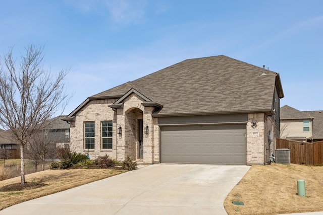 view of front facade featuring brick siding, a shingled roof, fence, a garage, and driveway